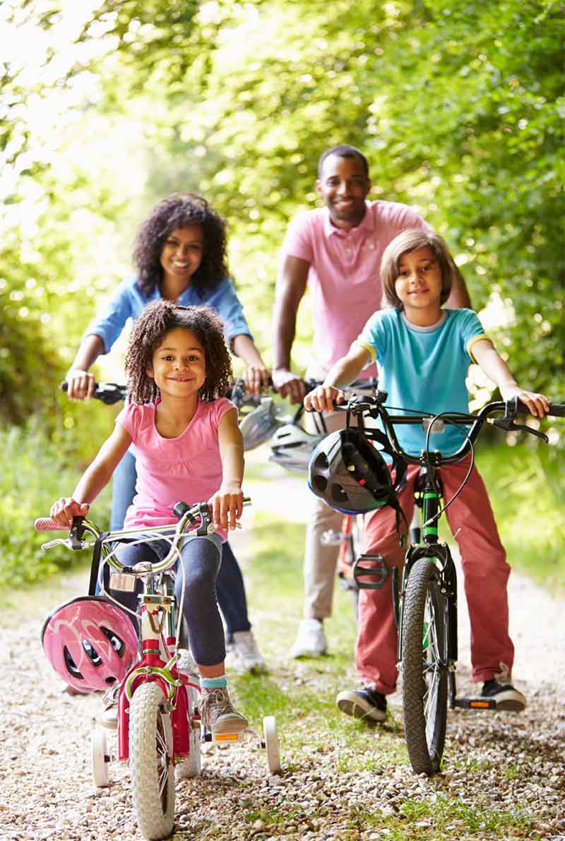 family-riding-bike-through-park family taking a bike ride through park