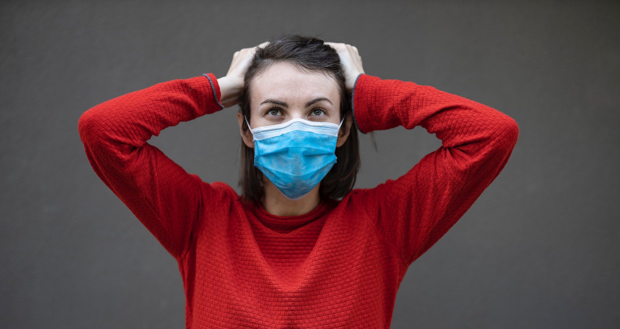 woman wearing a face mask and holding her head